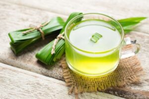 a cup of pandan tea and a bowl of pandan leaves